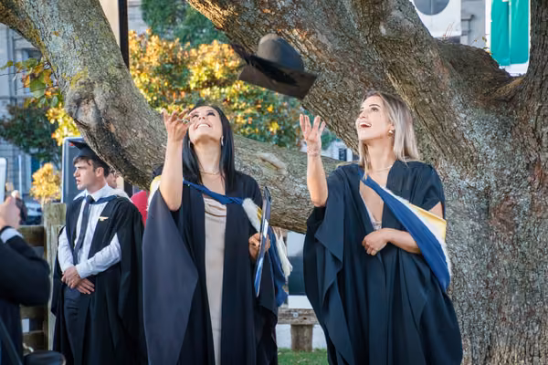 Two Massey graduates celebrating after a graduation ceremony.