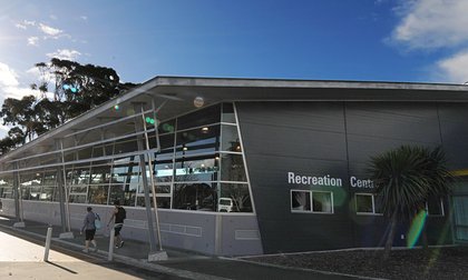 Exterior of the corner of the Recreation Centre building, with two people walking outside, wearing gym gear