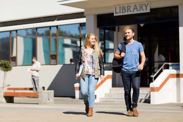 Two students walking outside library