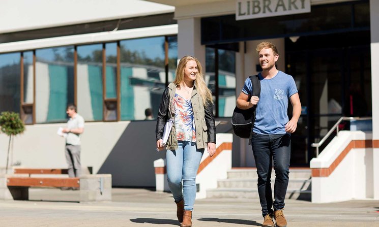 Two students walking outside library