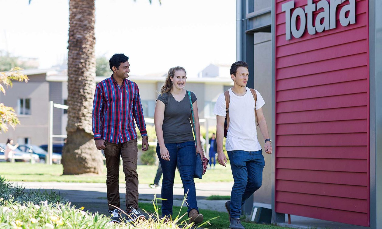 Three students walking past the Totara accommodation building