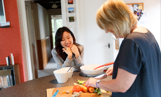 Two people standing at a kitchen bench while they prepare a range of vegetables