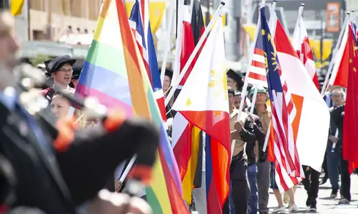 People attending a graduation procession, holding the colourful flags of different countries