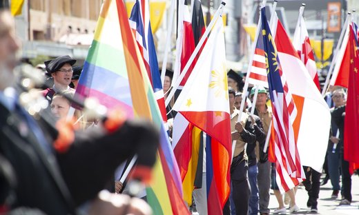 People attending a graduation procession, holding the colourful flags of different countries