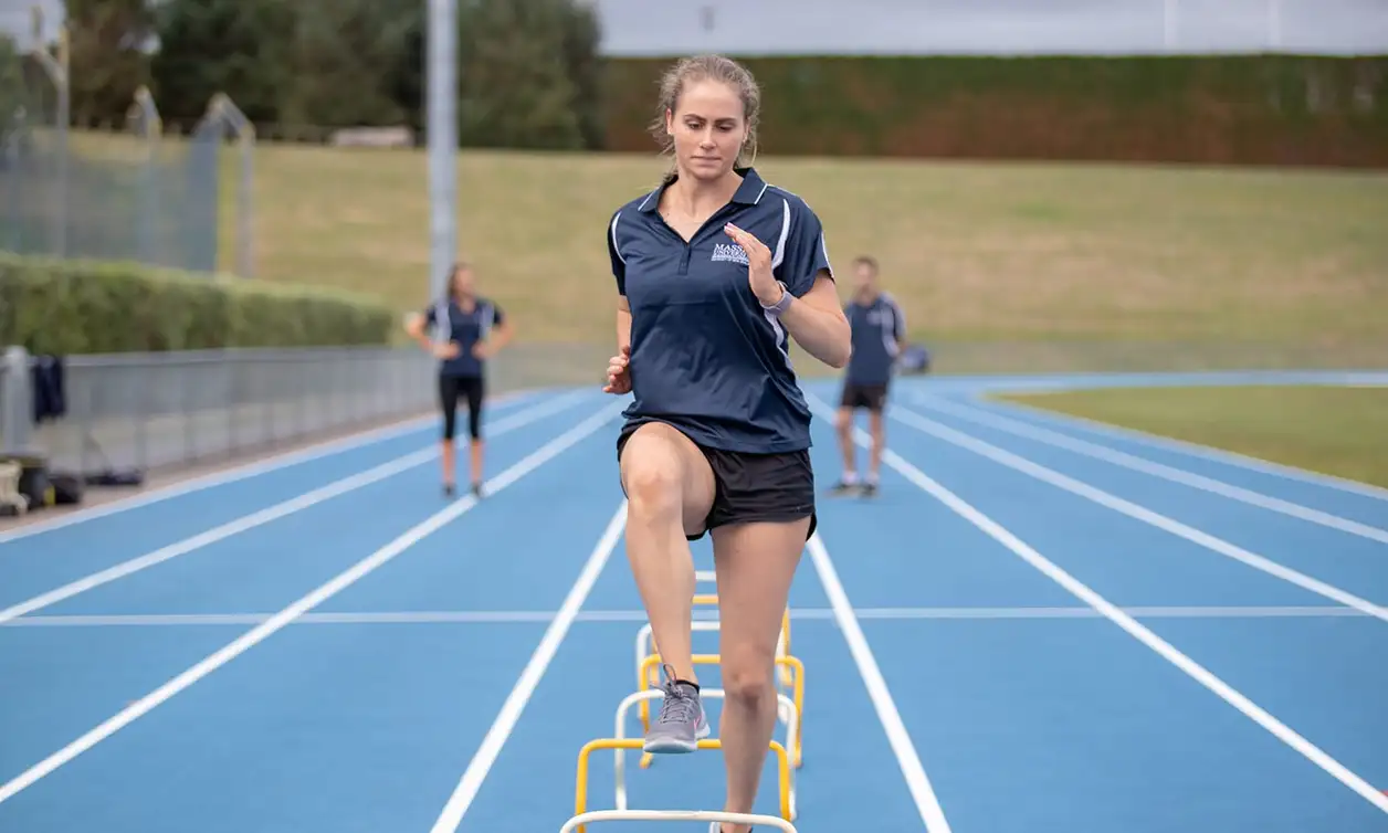 Student stepping over small hurdles on an athletics track