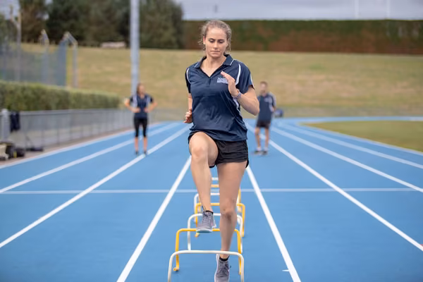 Student stepping over small hurdles on an athletics track