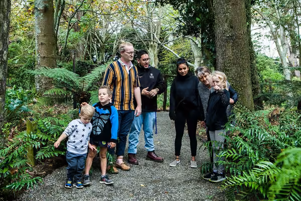 Small group of adults and children standing in a forest clearing