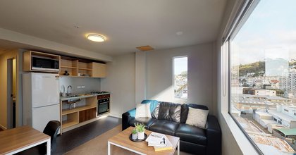 Lounge in The Cube apartment, with fridge, kitchenette, tables and couch and Wellington city views