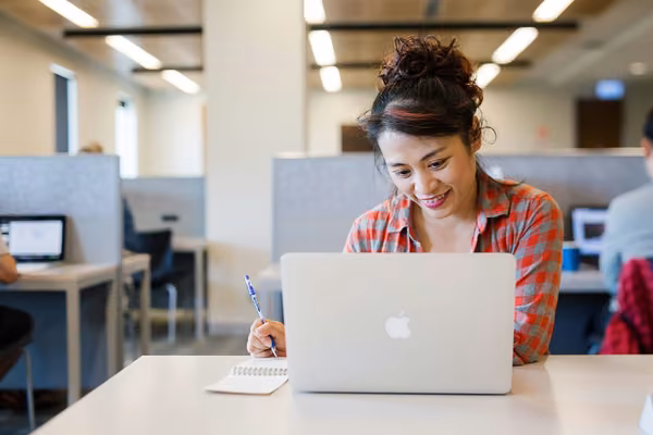 Student using a laptop at a desk in the library