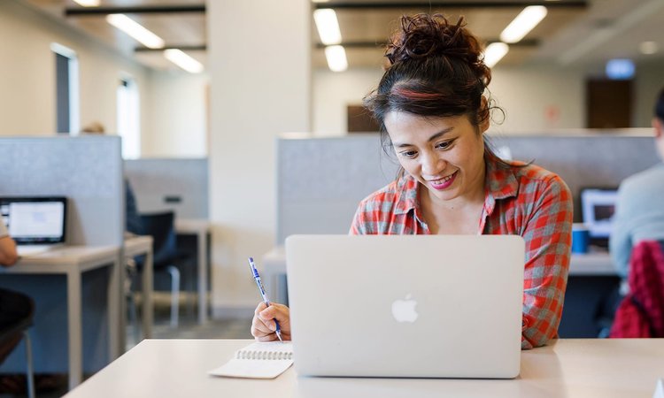 Student using a laptop at a desk in the library