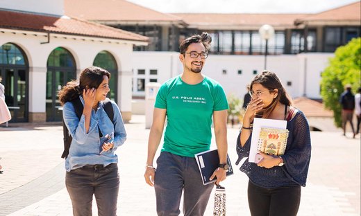 Three students talking and laughing on campus