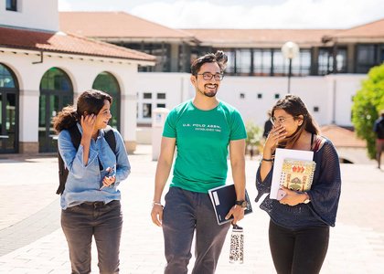 Three students talking and laughing on campus