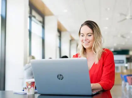 Student sitting at a table in a cafe, using a laptop