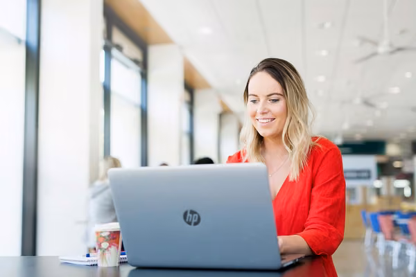 Student sitting at a table in a cafe, using a laptop