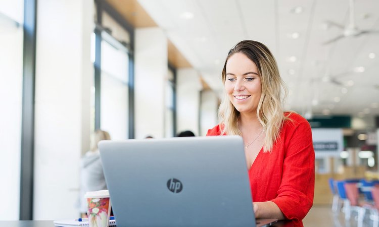 Student sitting at a table in a cafe, using a laptop