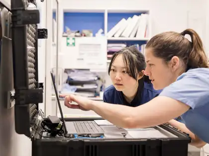 Two vet students looking at computer screen together.