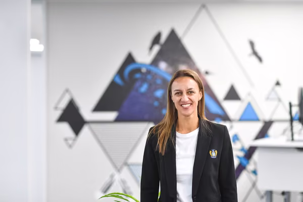 A person in a blazer standing and smiling at Massey.