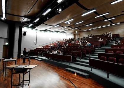 Lecture theatre half-filled with seated students