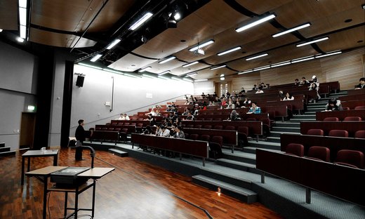 Lecture theatre half-filled with seated students