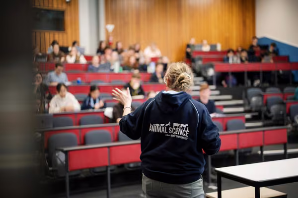 woman speaking to lecture hall full of students