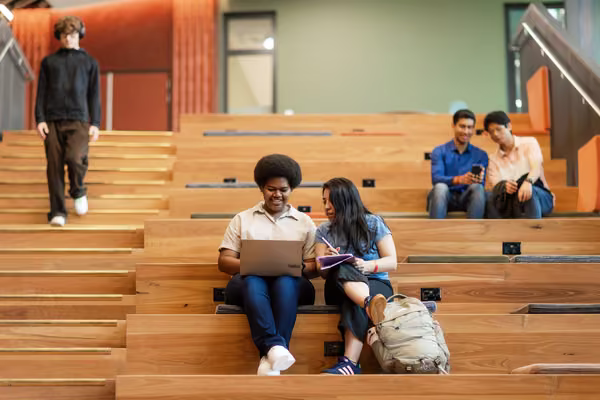 Students sit on the stairs in the Innovation Complex on Massey's Auckland campus.
