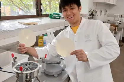 man in lab coat holding two paper circles and smiling