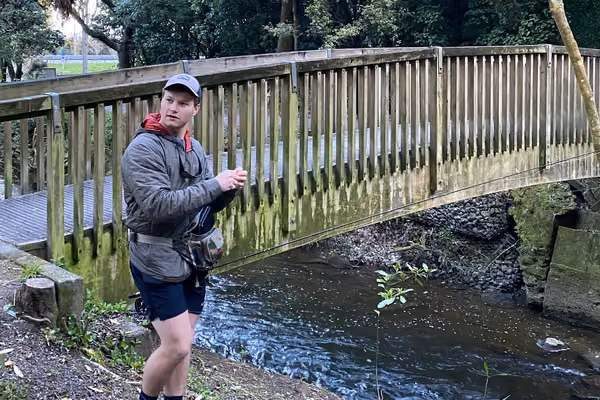 man standing in front of bridge over river