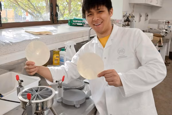 man in lab coat holding two paper circles and smiling