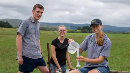 Three young people in a paddock with a water sample