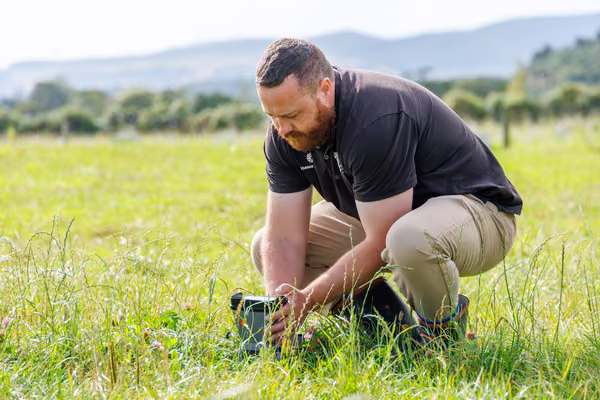 man standing in field examining equipment