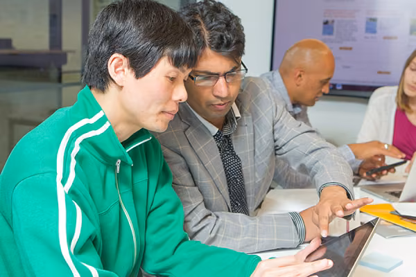 Teacher helping a student learn using an iPad.