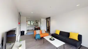 Matipo, Titoki and Tānekaha apartments' lounge area with couches, coffee table and wall mounted TV