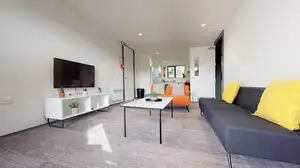 Matipo, Titoki and Tānekaha apartments' lounge area with couches, coffee table and wall mounted TV