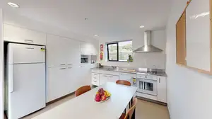 Matipo, Titoki and Tānekaha apartments' kitchen with fridge, bench top, oven and a dining table with chairs
