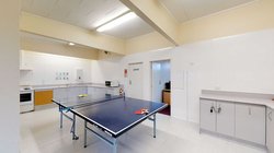 Interior of Atawhai Flats common room with table tennis table, kitchenette and cupboards