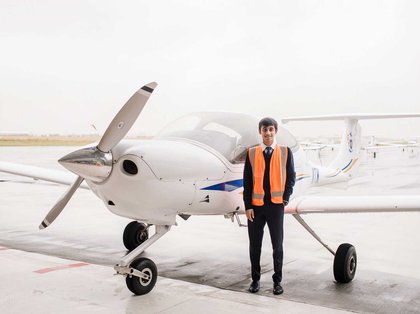 Youthful person standing next to a small plane