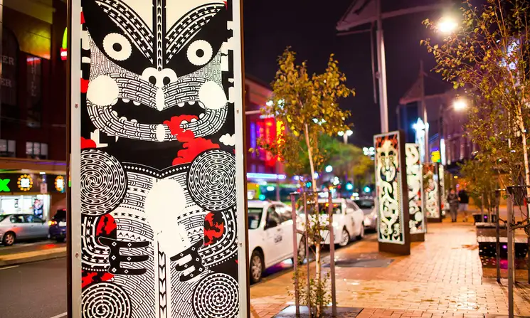 Night street scene, showing pillars with unique black and red Maori designs