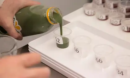 Pouring green juice into plastic cups.