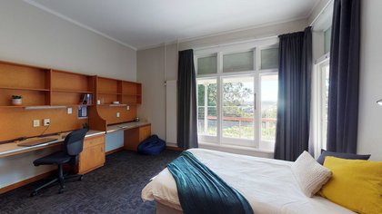 Interior of Bindaloe Hall's double bedroom with bed, dual built-in desks and a large window