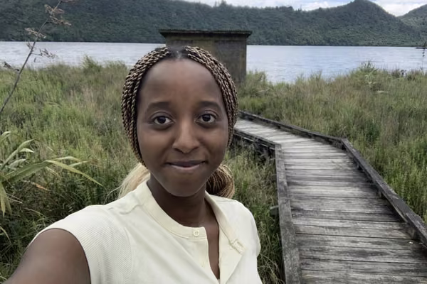 girl smiling at camera standing outside near dock and water
