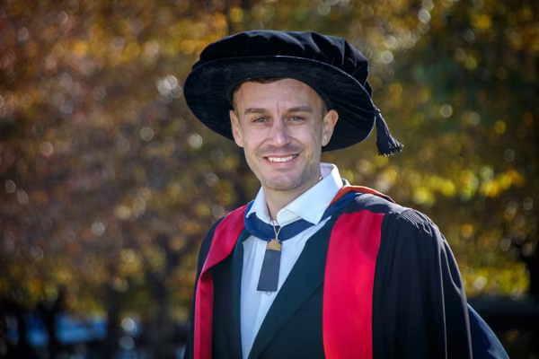 man smiling at camera in graduation gear