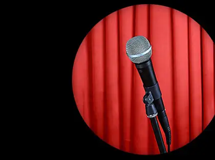 A spotlight on a microphone in front of a red curtain.