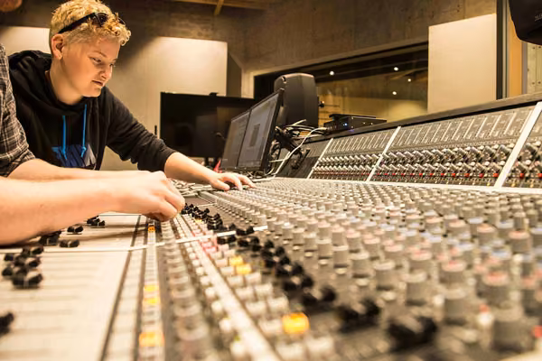 Close up of a large mixing desk with two people
