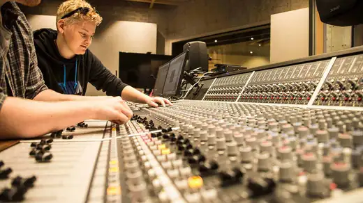 Close up of a large mixing desk with two people