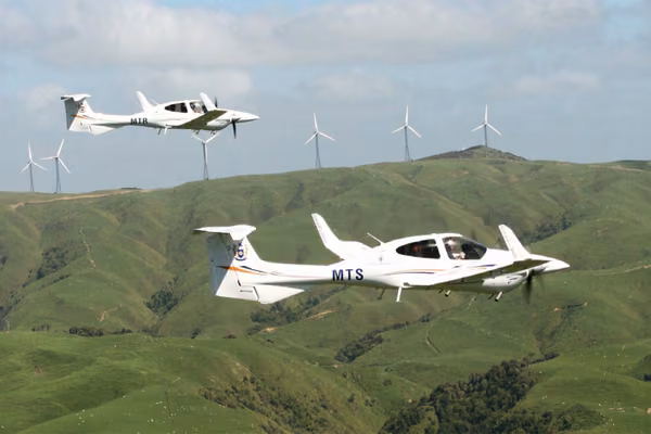 Diamond aircraft in flight with wind turbines in background