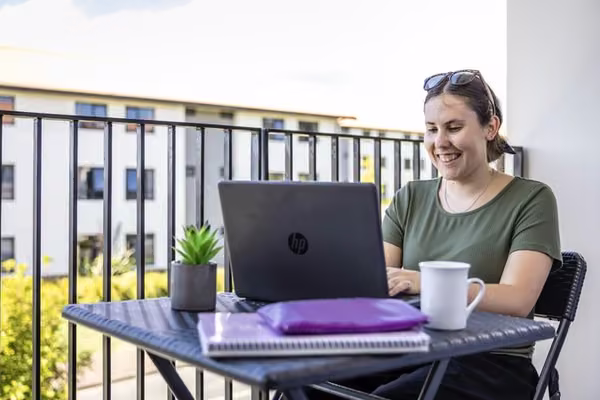 Student studies on a balcony in the sun