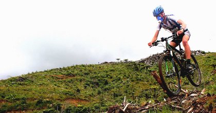 Mountain bike rider airborne while crossing rugged terrain, and wearing a mask