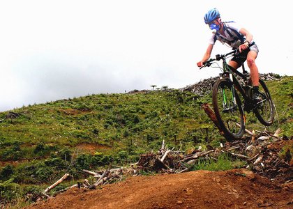 Mountain bike rider airborne while crossing rugged terrain, and wearing a mask