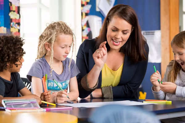 Teacher with primary school students and colourful pens