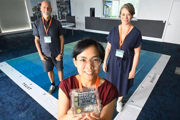Three smiling people with a Raspberry Pi